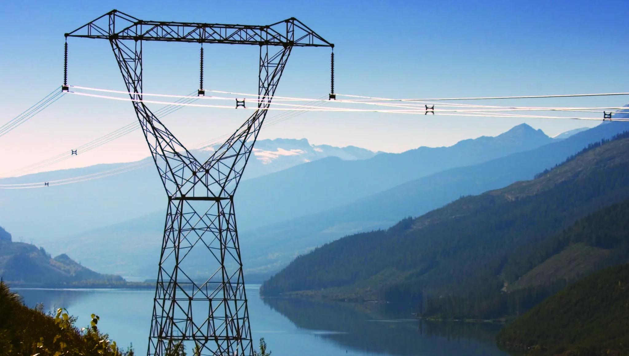 500 kV transmission towers crossing a mountain lake corridor