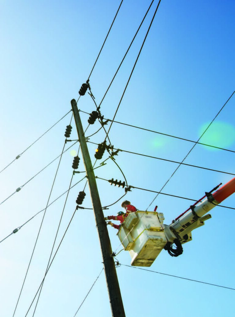 Line crew in an insulated bucket working on an energised overhead distribution pole