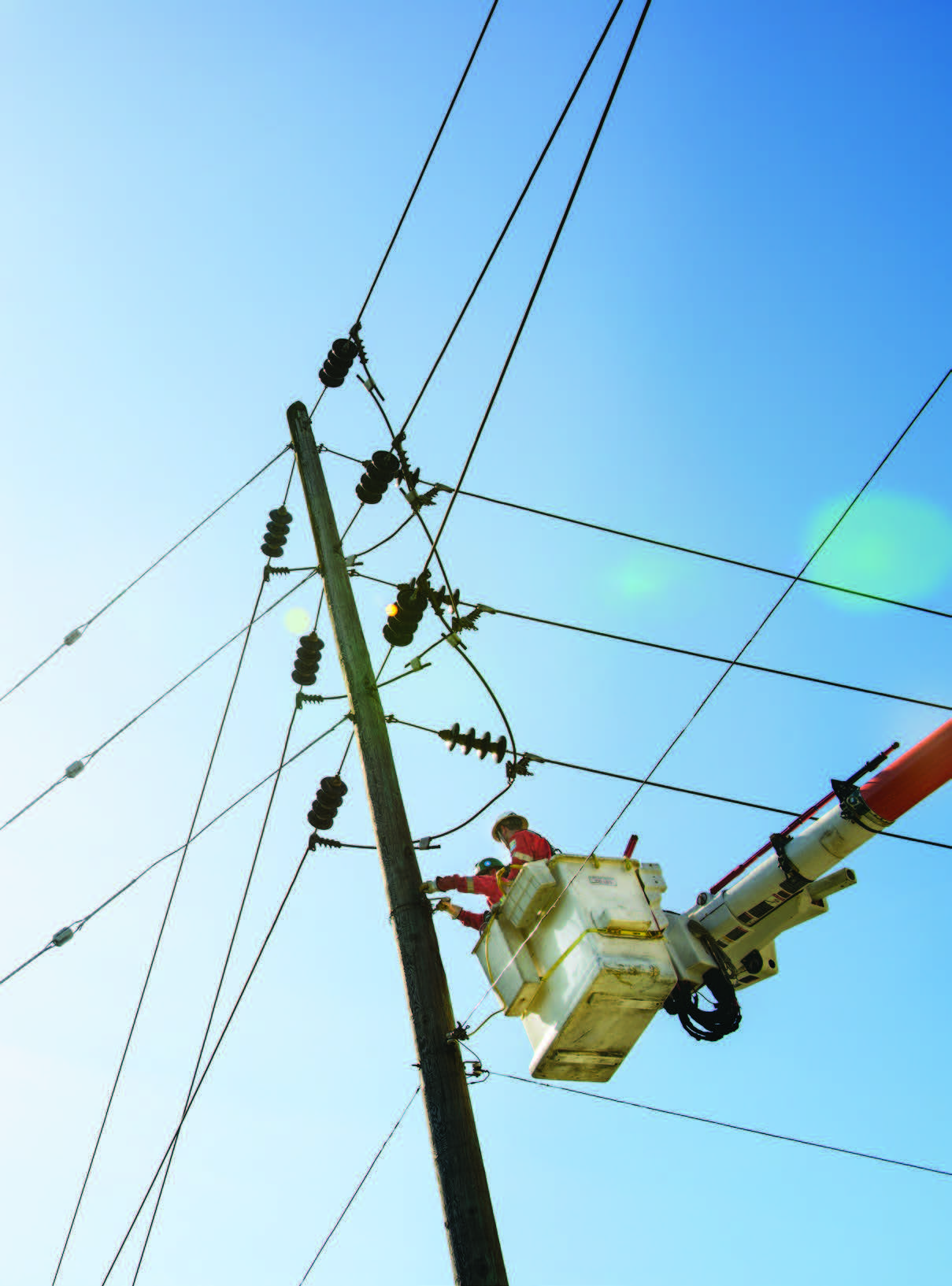 Line crew in an insulated bucket working on an energised overhead distribution pole
