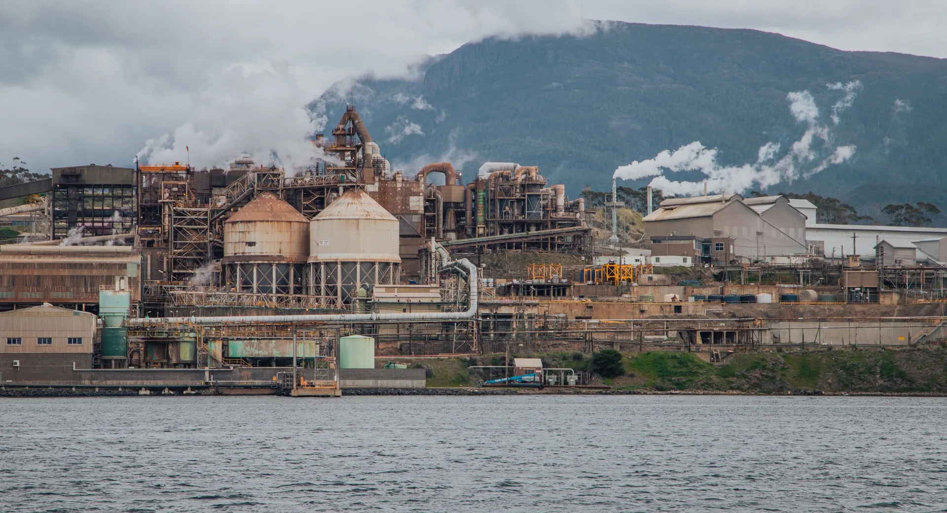 Copper smelter complex with process buildings and stacks beside a waterway