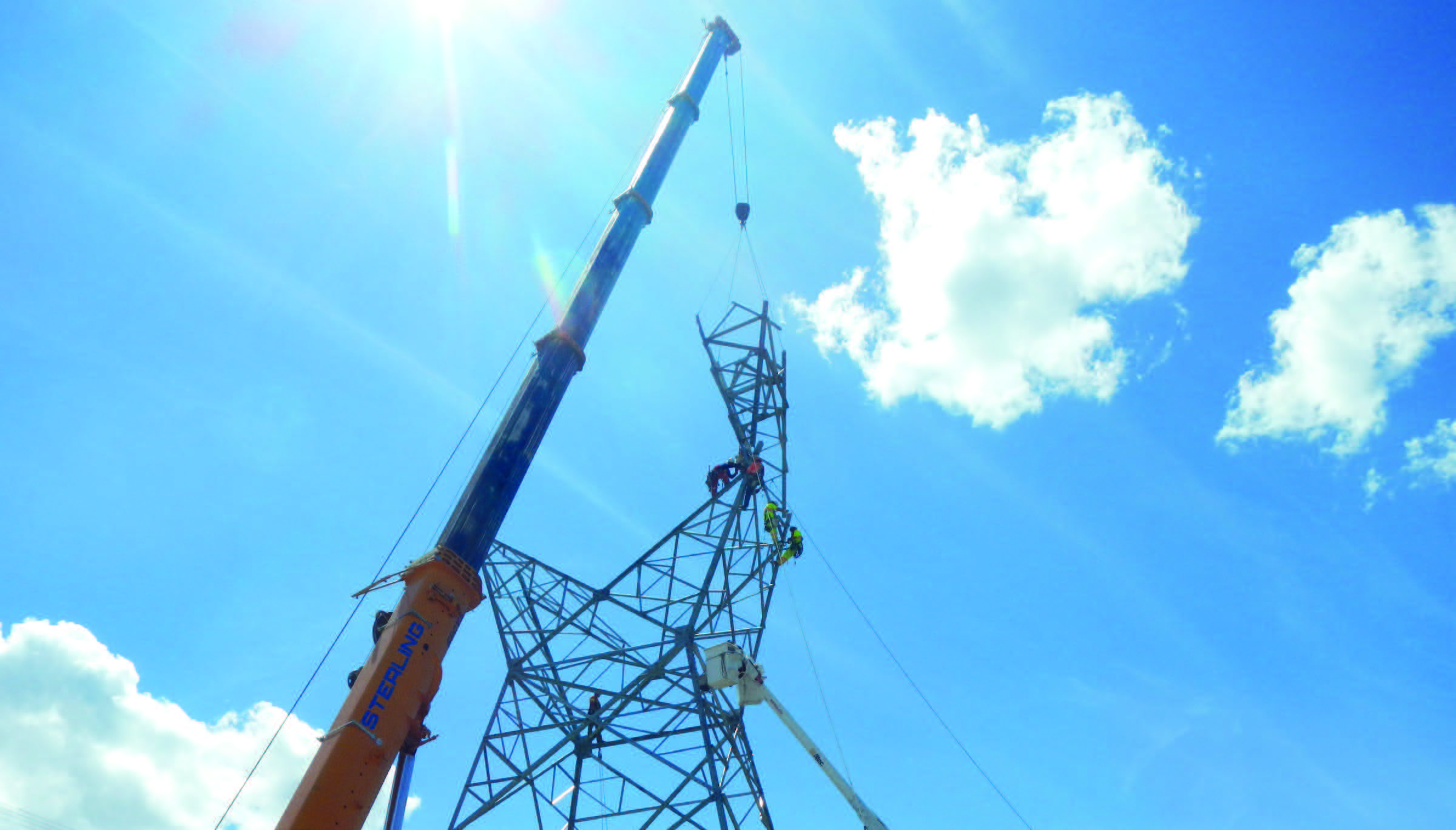 Mobile crane lifting steel sections during erection of a lattice transmission tower
