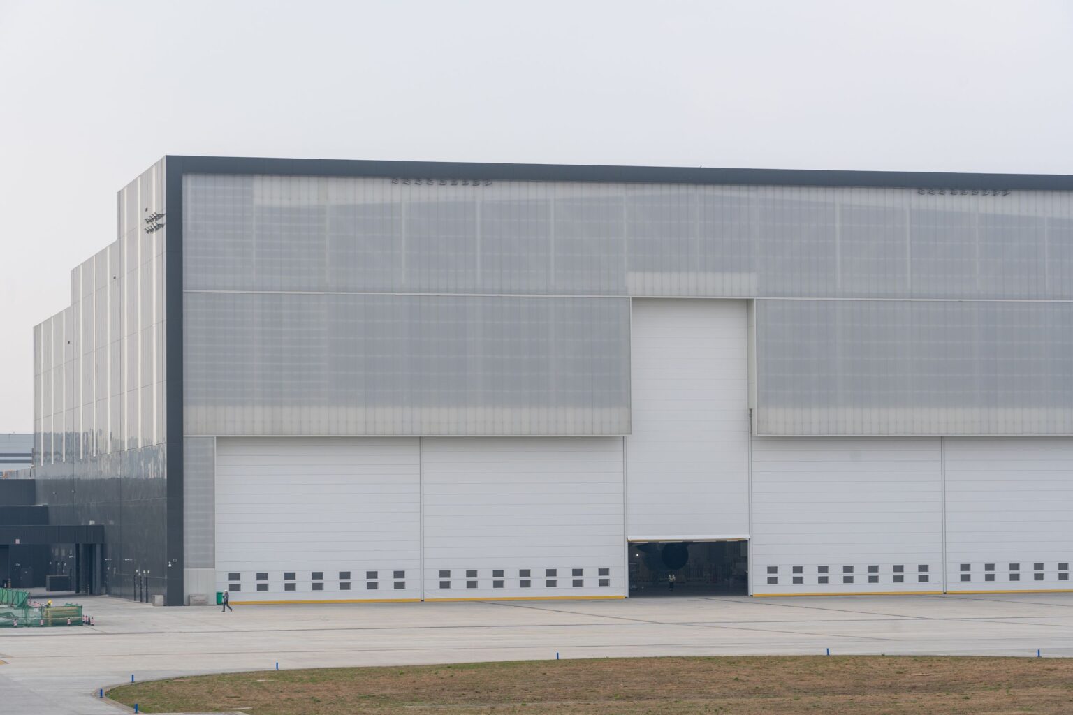 Exterior of a large industrial hangar with metal cladding and roller doors