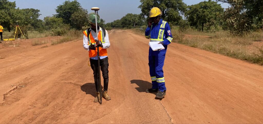 Surveyors walking the laterite road alignment with a GNSS rover between Kome 4 and Doba, Chad