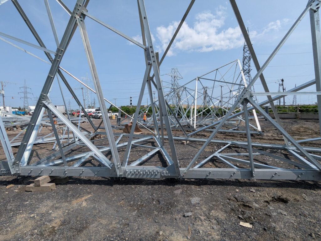 Galvanised lattice steel transmission tower sections laid out in an assembly yard before erection