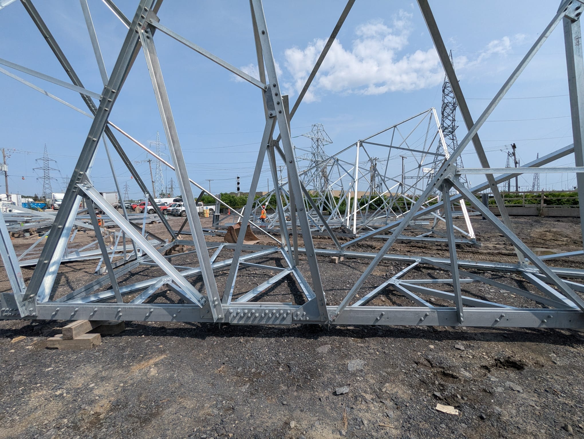 Galvanised lattice steel transmission tower sections laid out in an assembly yard before erection